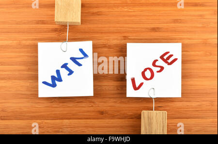 Win lose, two white paper notes with marker hand written words, wooden holders in different directions on bamboo wooden backgrou Stock Photo