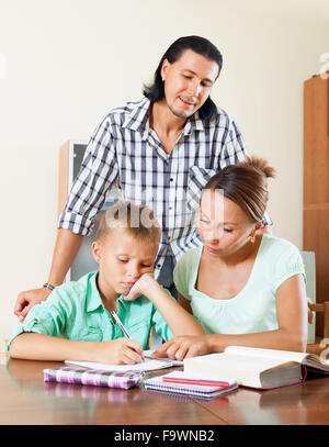 Teenager schoolboy and parents together doing homework in home Stock Photo