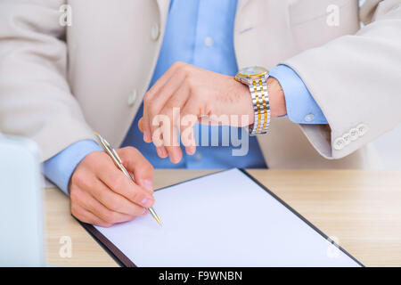 Businessman checking the time while doing paperwork. Stock Photo