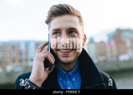 Ireland, Dublin, portrait of smiling young businessman telephoning with smartphone Stock Photo