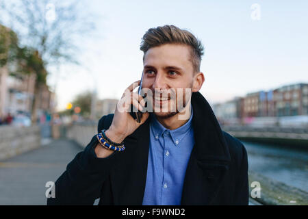 Ireland, Dublin, portrait of young businessman telephoning with smartphone Stock Photo