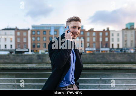 Ireland, Dublin, portrait of young businessman telephoning with smartphone Stock Photo