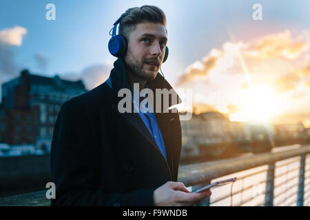 Ireland, Dublin, young man hearing music with headphones at twilight Stock Photo