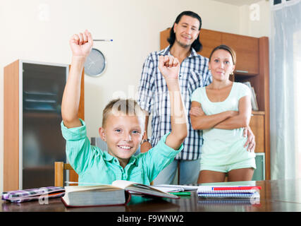 Teenager schoolboy doing homework near his cheerful parents Stock Photo