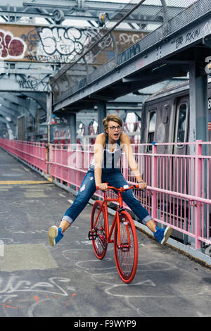 USA, New York City, Williamsburg,  woman with red racing cycle on Williamsburg Bridge Stock Photo