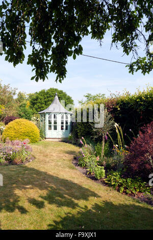 UK gardens. An octagonal painted summerhouse in a summer garden. Stock Photo
