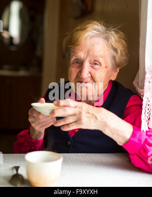 Happy old woman drinking tea in the kitchen. Stock Photo