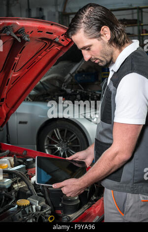 Mechanic using a tablet pc at the repair garage Stock Photo