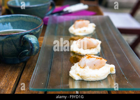 Close up of pan seared sea scallops and a cup of cider. Shot with a selective focus Stock Photo