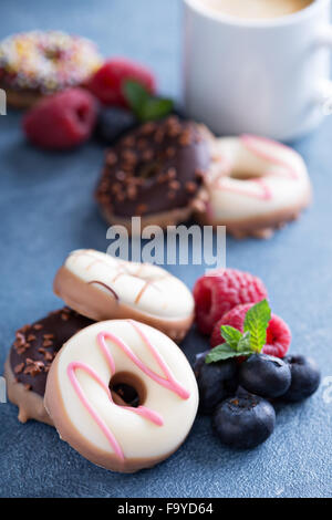 Small glazed mini donuts with fresh raspberries and blueberries Stock Photo