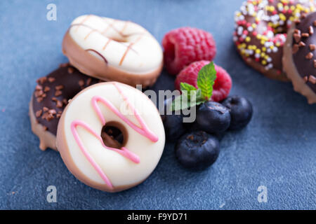 Small glazed mini donuts with fresh raspberries and blueberries Stock Photo