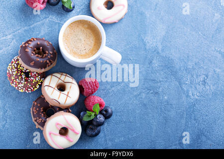 Small glazed mini donuts with fresh raspberries and blueberries Stock Photo