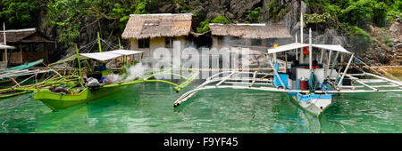 Two wooden Boats in Front of Nipa wood house on stilts at the sea Stock Photo