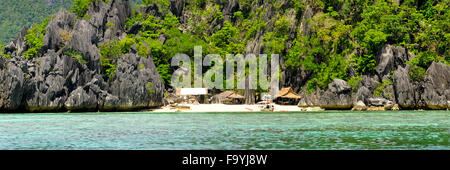 Rocky Island With Nipa Huts houses on a lonely White Sand beach Stock Photo