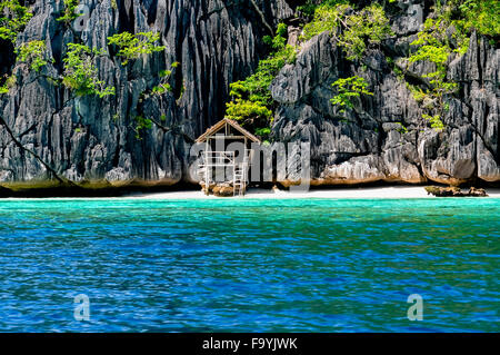 Lonely wooden bamboo house on stilts at a small hidden beach of rocky island Stock Photo