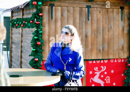 the beautiful woman at a table against the decorated wooden house for Christmas, a subject the woman and holidays Christmas and Stock Photo