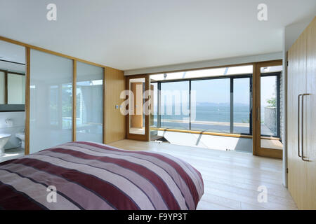 The master bedroom of a house on the cliffs on the sea. Glass panels. Light airy space. Stock Photo