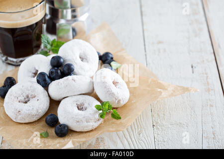 Powdered sugar donuts on parchment with blueberries and mint Stock Photo