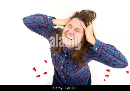 Expressive portrait of a beautiful girl with her hands to her ears screaming, studio shot on white background. Stock Photo