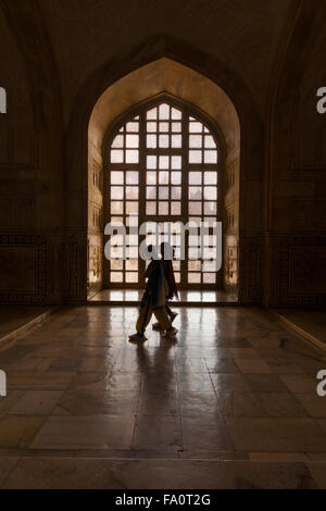 Two unidentified Indian women walking in front of a lattice window gate inside the inner hallway of the Taj Mahal Stock Photo