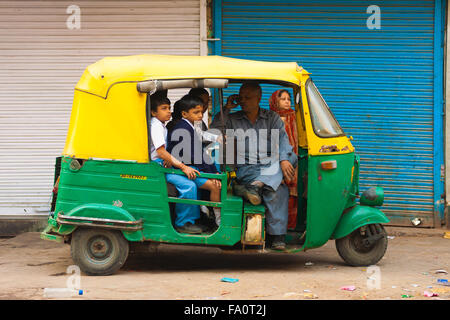 Young children crammed into a private auto rickshaw waiting patiently to be transported to school while driver talks on mobile Stock Photo