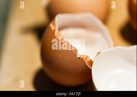 Macro close-up of empty cracked brown egg shells against brown background. Stock Photo