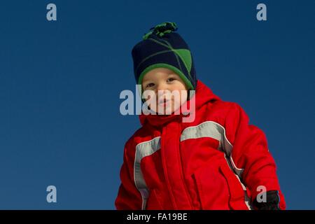 Winter portrait of a young boy on a background of blue sky Stock Photo