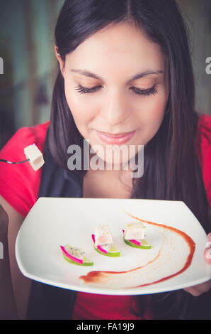 Beautiful young woman enjoying a delicious seafood plate with tuna, lemon and pitahaya Stock Photo
