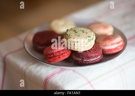 Christmas macarons - frosted cranberry, vanilla basil, mulled wine and candycane flavours on checked tablecloth Stock Photo