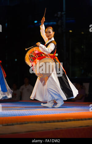 A traditionally dressed Korean in hanbok woman on stage playing traditional janggu drums at a free summer show near city hall Stock Photo