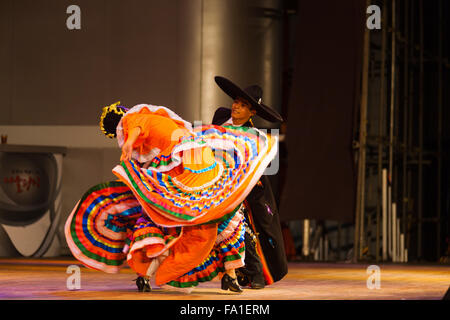 Female dancer bending and twisting her body in orange swirling and fluttering dress at Mexican Jalisco sones dance show Stock Photo