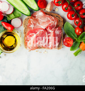 Slice of a whole wheat bread and healthy organic vegetables for making sandwiches. Healthy eating or cooking concept. Background Stock Photo