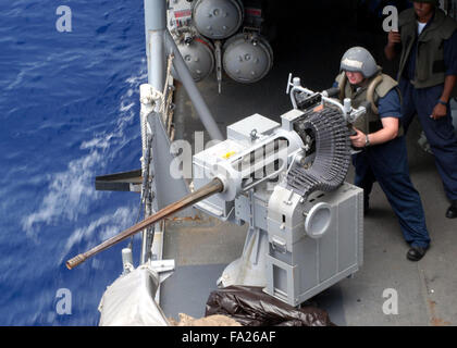 Operations Specialist defends the ship with a Mark 38 .25mm machine gun during a small boat training exercise aboard the guided missile frigate USS Ingraham Stock Photo