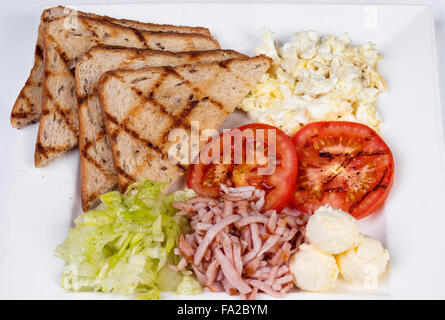 Traditional English breakfast with scrambled eggs, tomatoes, potatoes, toast and fresh salad
