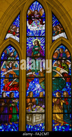 Stained Glass window depicting Saint John the Evangelist surrounded by angels in the Almudena cathedral of Madrid Stock Photo