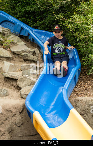 Seven year old boy going down a slide in Seattle, Washington, USA Stock Photo