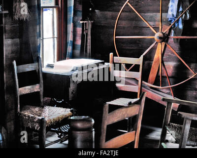 Interior of a log cabin with a spinning wheel and cane chairs at the Pioneer Village, Great Smoky Mountains National Park, USA. Stock Photo