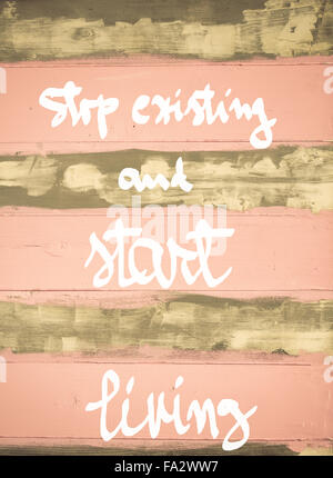 Concept image of Stop Existing and Start Living motivational quote hand written on vintage painted wooden wall Stock Photo