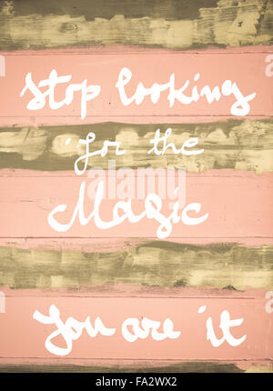 Concept image of Stop Looking For the Magic, you are it motivational quote hand written on vintage painted wooden wall Stock Photo