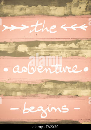 Concept image of The Adventure Begins motivational quote hand written on vintage painted wooden wall Stock Photo