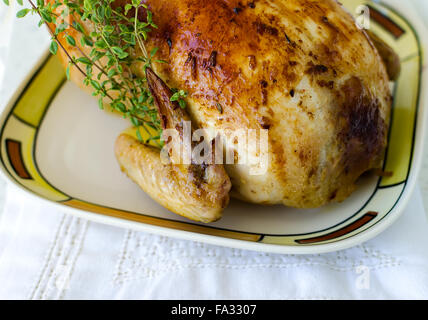 Roasted whole chicken stuffed with chestnuts and mushrooms on white tablecloth Stock Photo