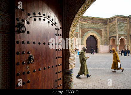 People with djellaba walking in front of The Bab el Mansour gate, view from inside a entry hall of a classical building. Meknes. Stock Photo