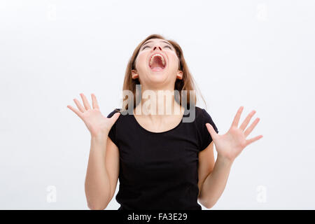 Crazy hysterical young woman screaming and looking up over white background Stock Photo