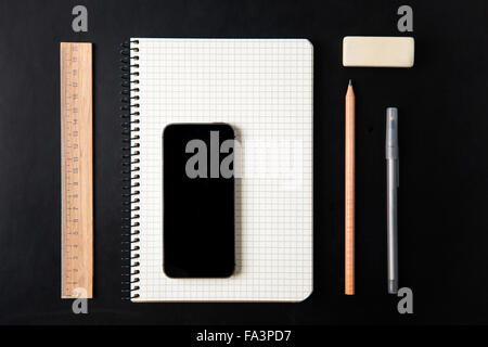 Top view of school supplies and blank screen mobile phone isolated over black background Stock Photo