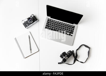 Top view of two cameras, notepad with pen and blank screen laptop isolated over white background Stock Photo