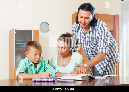 Ordinary family of three doing homework in home interior Stock Photo