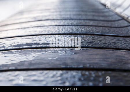Drops of morning dew on a wooden bench in the park Stock Photo