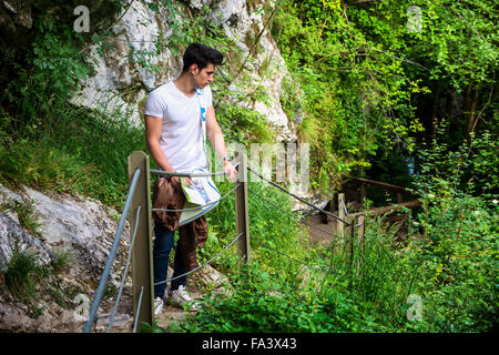 Handsome young man sitting in natural park, looking away Stock Photo