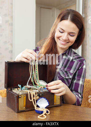 portrait of happy girl chooses jewelry in treasure chest at home Stock Photo