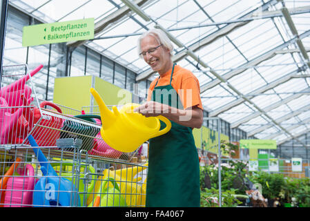 Male gardener arranging colourful watering cans, Augsburg, Bavaria, Germany Stock Photo